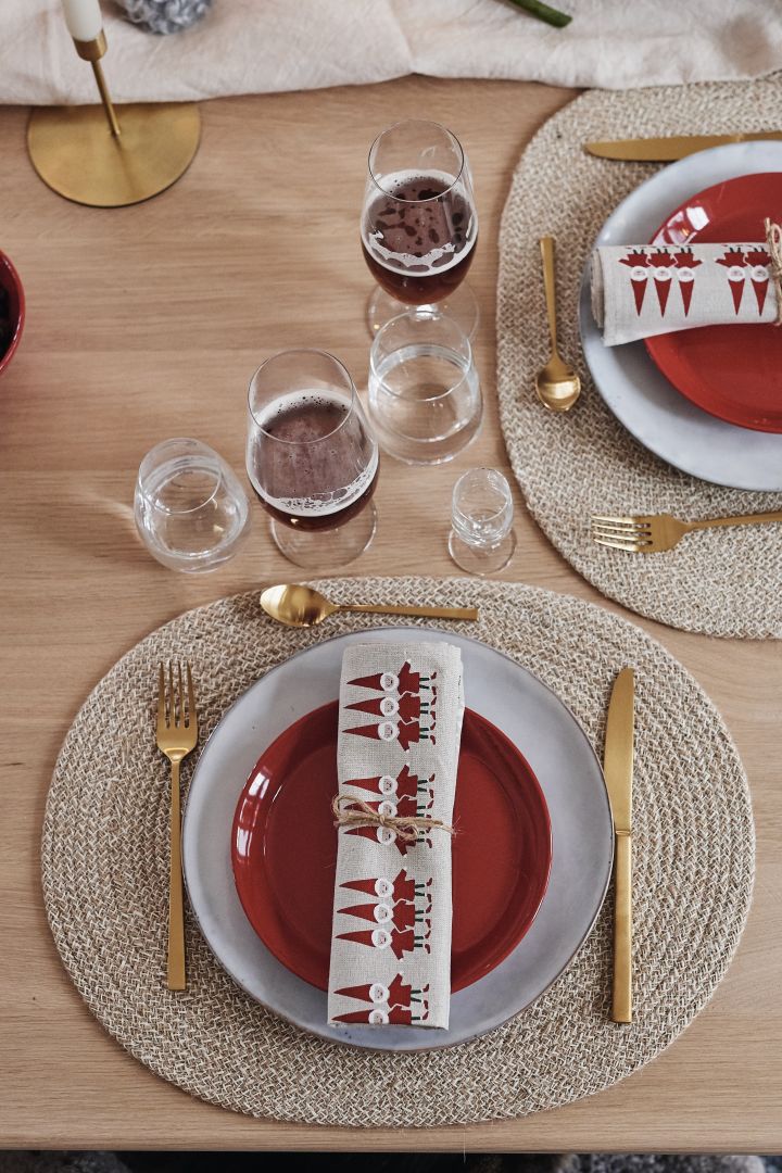 En enkel juldukning där tallrikskuvertet består av blågrå mattallrik, röd assiett och guldbestick. 