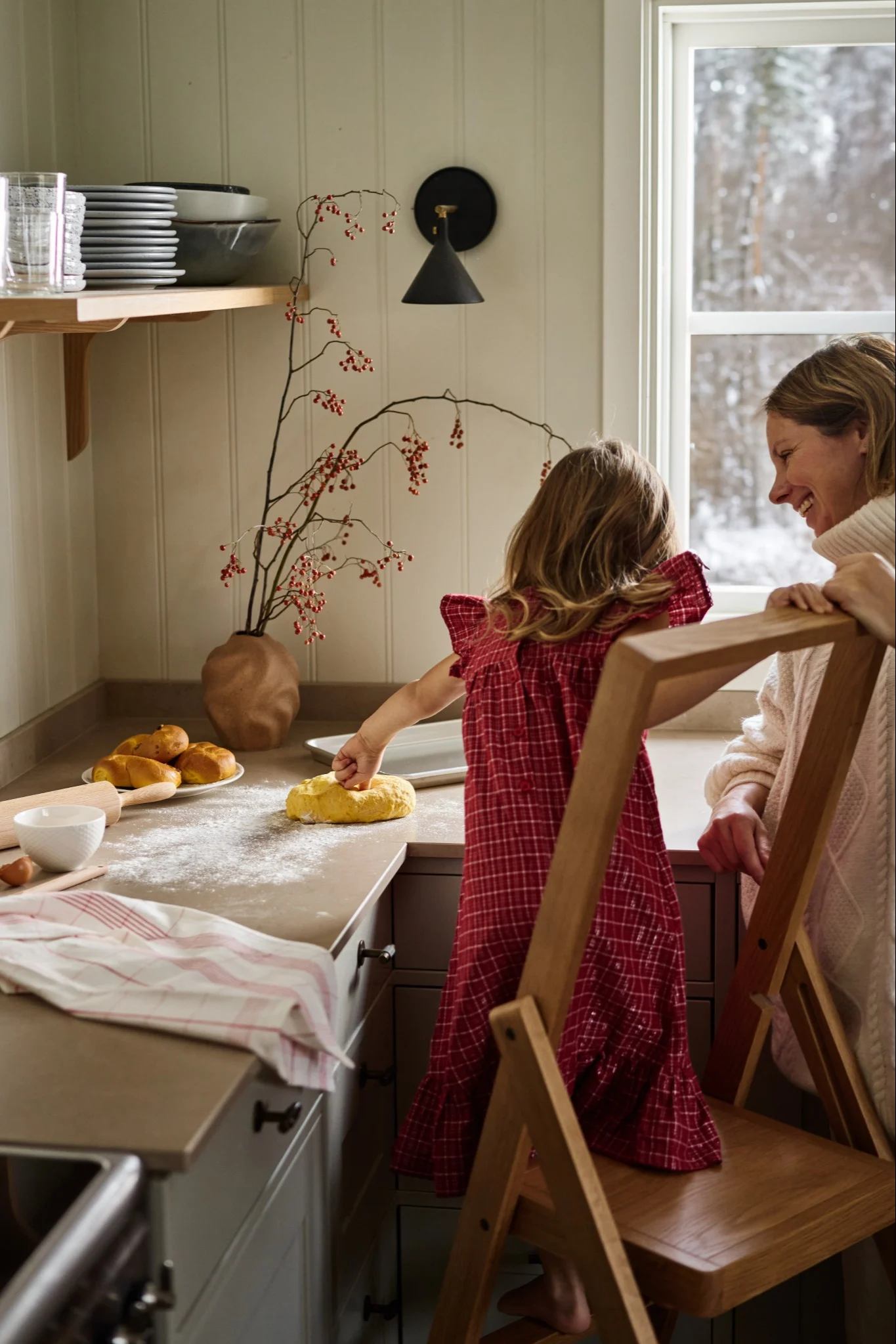 Ett barn och en vuxen står i ett kök och julbakar som en aktivitet för att fira första advent. Barnet står på en Step stege från Design House Stockholm och knådar en saffransdeg. 