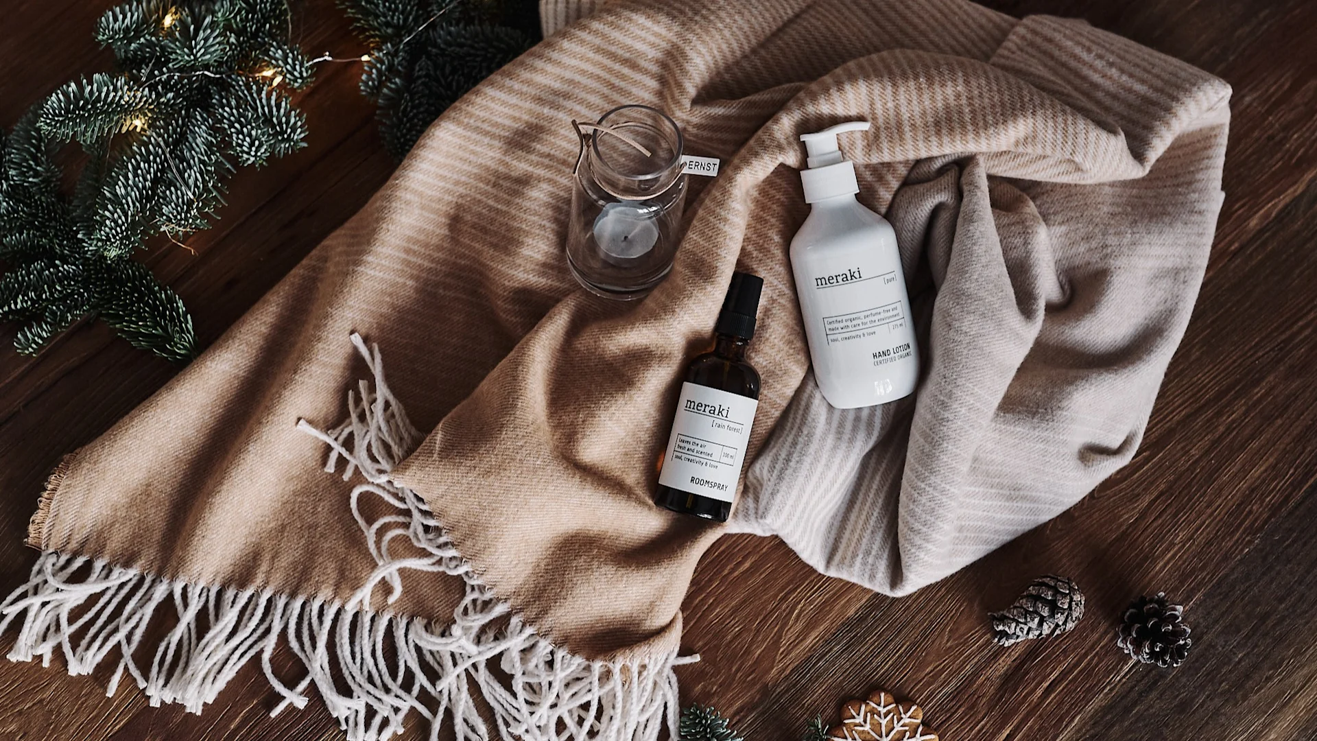 Handkräm och ljuslykta ligger på en bomullspläd som kommer användas till att slå in paketet med som ett sätt att tillämpa hållbar paketinslagning.