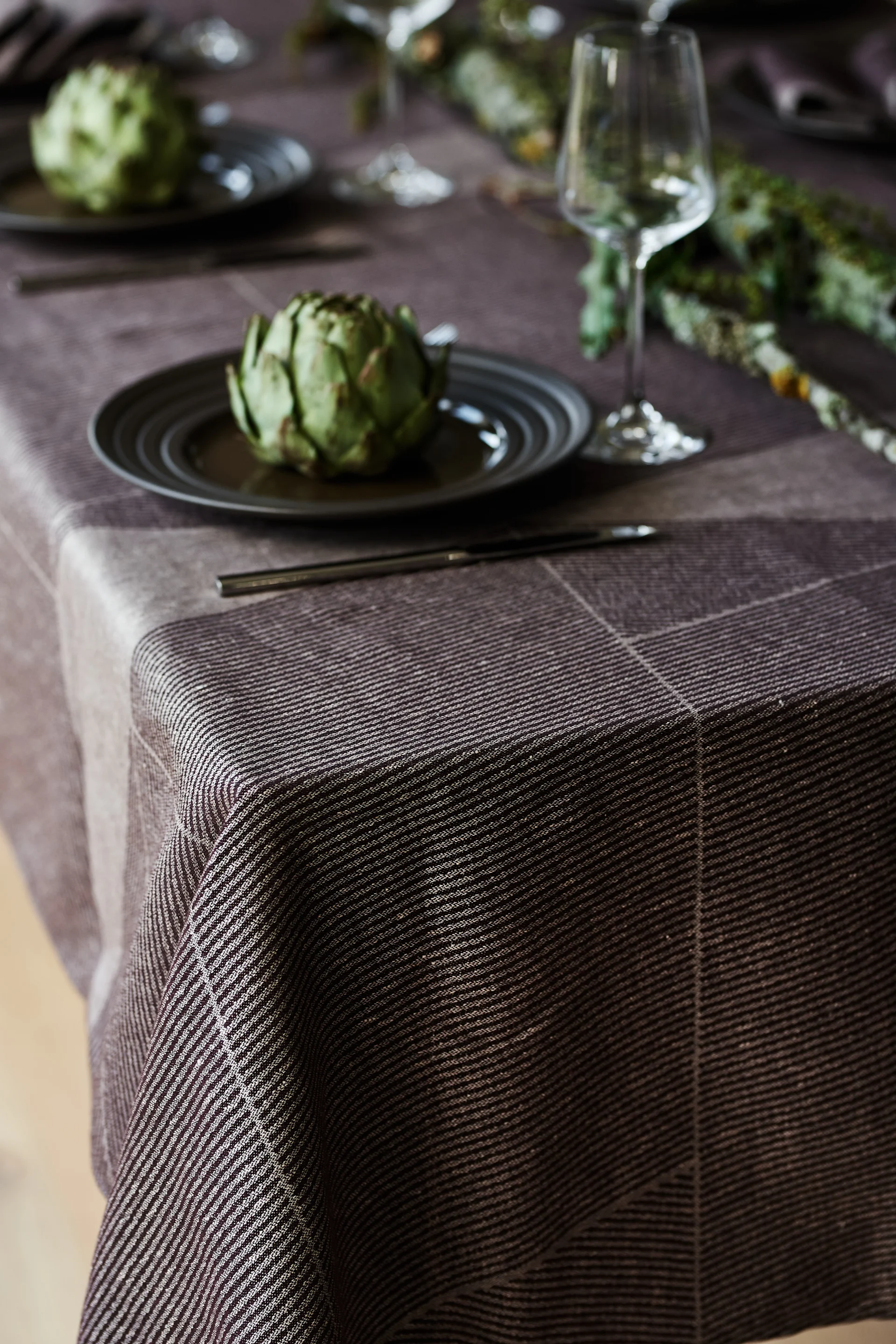 Skapa vackra festdukningar genom stilrena Scandi Living bestick, elegant Lines porslin från NJRD tillsammans med brun Geometric linneduk från NJRD.