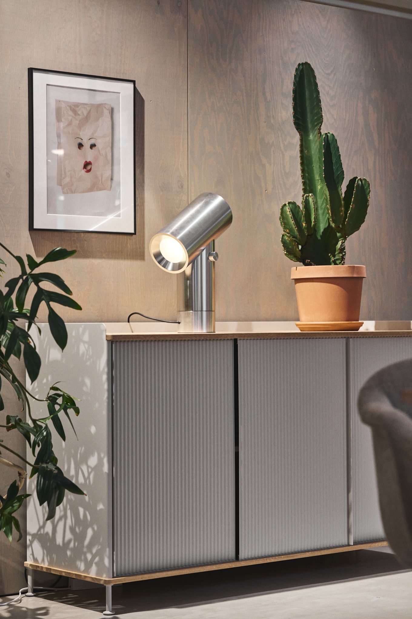 Den silverfärgade byrån Enfold från Muuto med en kaktus på toppen och den silverfärgade bordslampan Beam från Muuto.