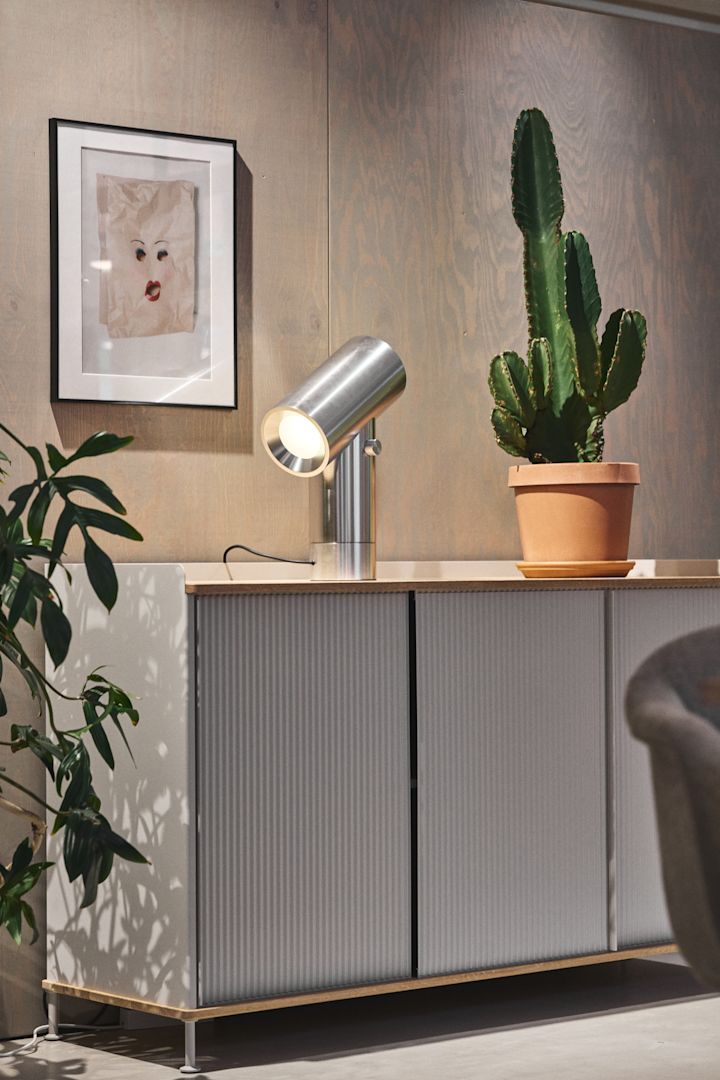 Den silverfärgade byrån Enfold från Muuto med en kaktus på toppen och den silverfärgade bordslampan Beam från Muuto.