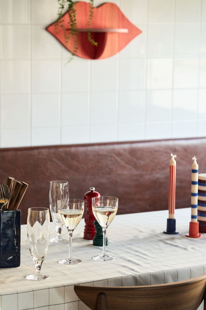 Chateau vitvinsglas från Kosta Boda på ett dukat bord med färgglada HAY-ljusstakar på bordet. 