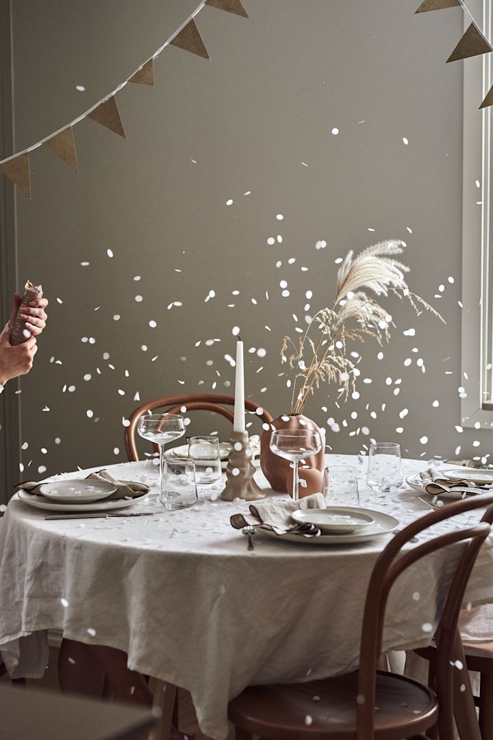 Hur man anordnar en fest med den perfekta stämningen, här ser du ett dukat bord med en nyligen exploderad party popper och konfettin som lägger sig på bordet. 