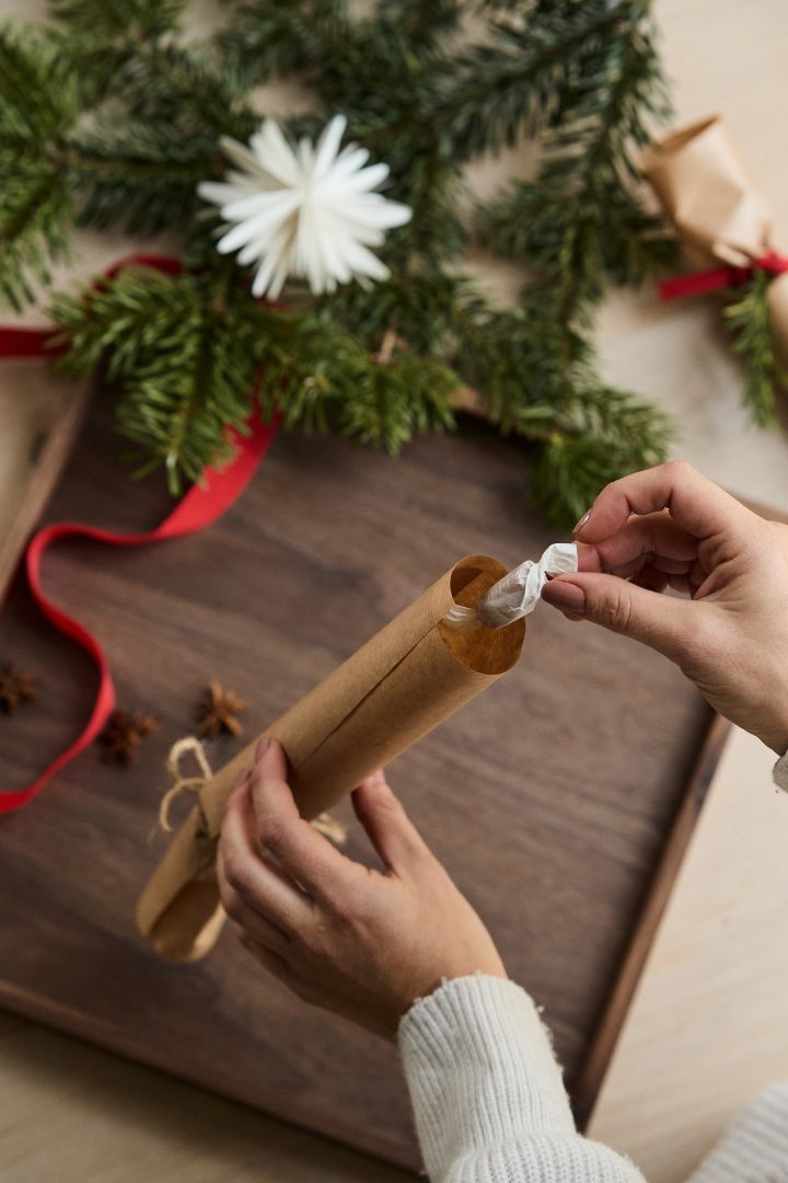 Lägg sedan i valfri gåva såsom en godisbit eller julgranshänge - vilket är steg 5 för att göra smällkarameller steg för steg.