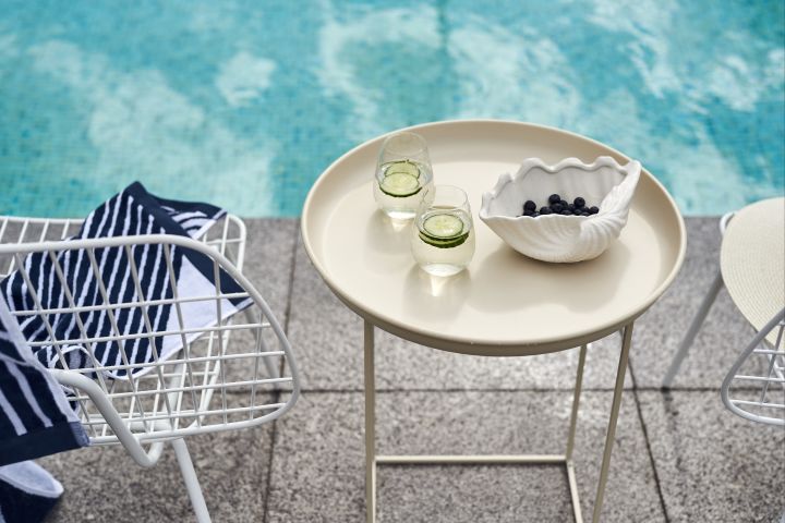 Ett beiged sidobord från Norr 11 är en sommarfavorit i sommar som pryds av Scandi Living vattenglas med gurkskivor i tillsammans med Shell skål från By On fylld med blåbär.