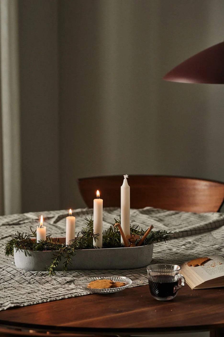 En adventsljusstake med riktiga ljus står på ett matbord och sprider julstämning. 