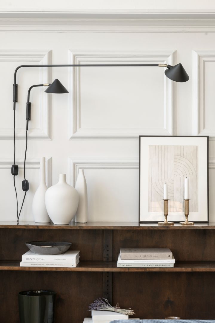 Förnya ditt hem med trendiga lampor - här ser du Kelly vägglampor i svart från Watt & Veke bredvid vaser och en tavla.