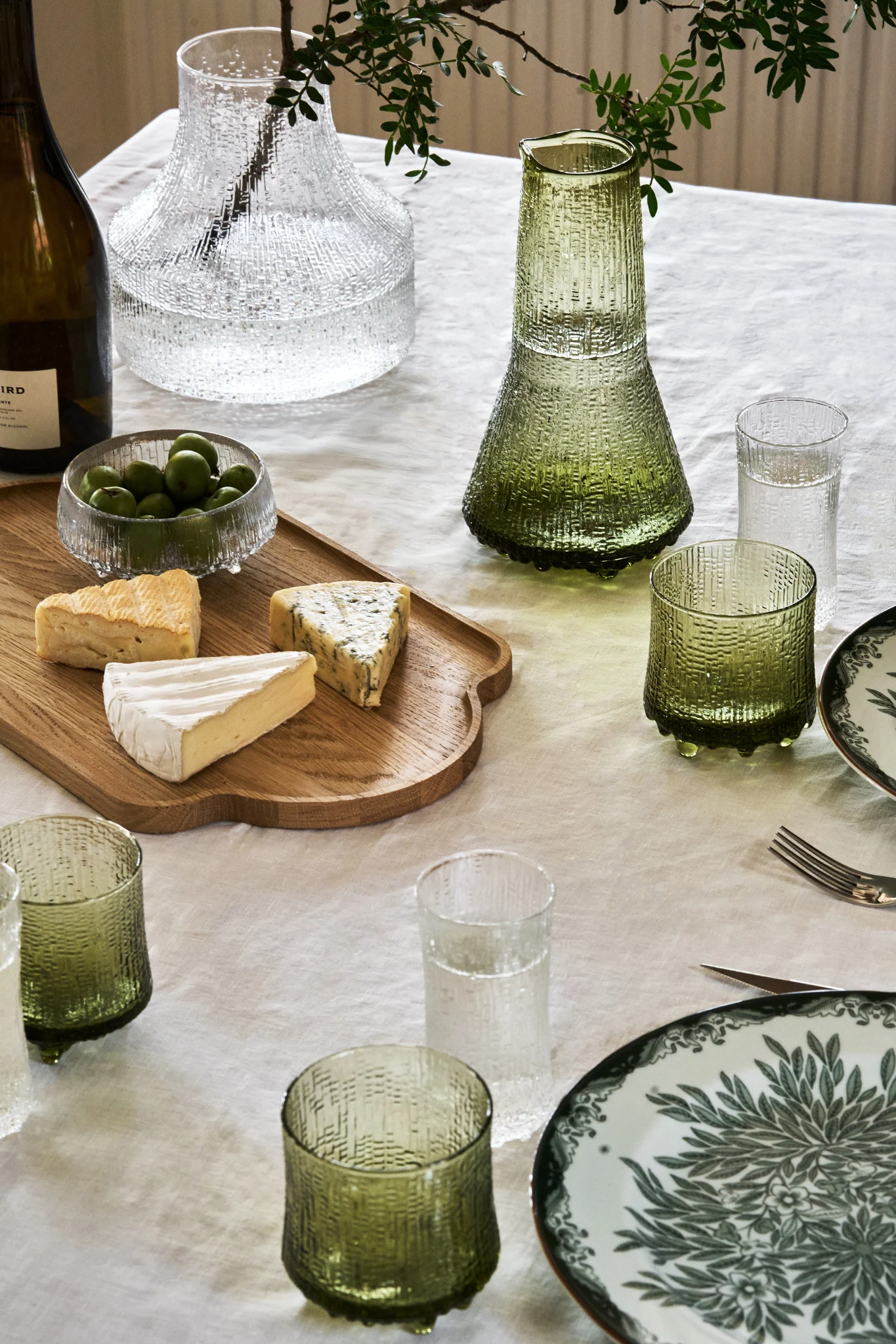 En grön juldukning 2025, där en stilren och inbjudande dukning visas tillsammans med en ostbricka.