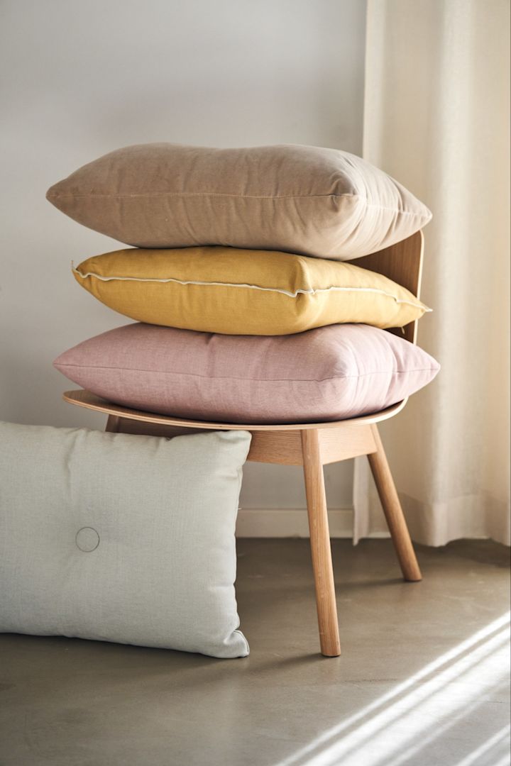 Hög med Dot Cushion Tint 1 dot kuddar i färgerna beige, rose och light grey tillsammans med Outline kudde i färgen Mustard från HAY.
