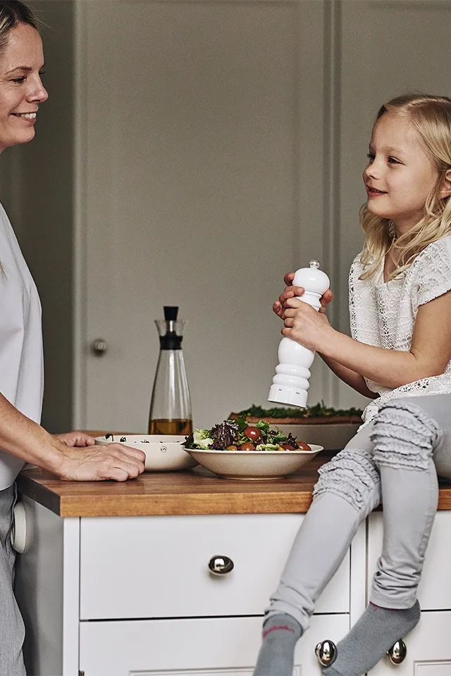Små som stora hjälps åt att tillaga salladen till middagen och familjens minsta saltar med Peugeot kryddkvarn vit.