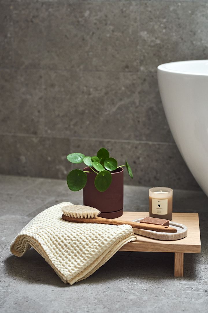 Badrum med inredning i japandi-stil med Kona sidobord från ferm living, brun kruka och spadetaljer.