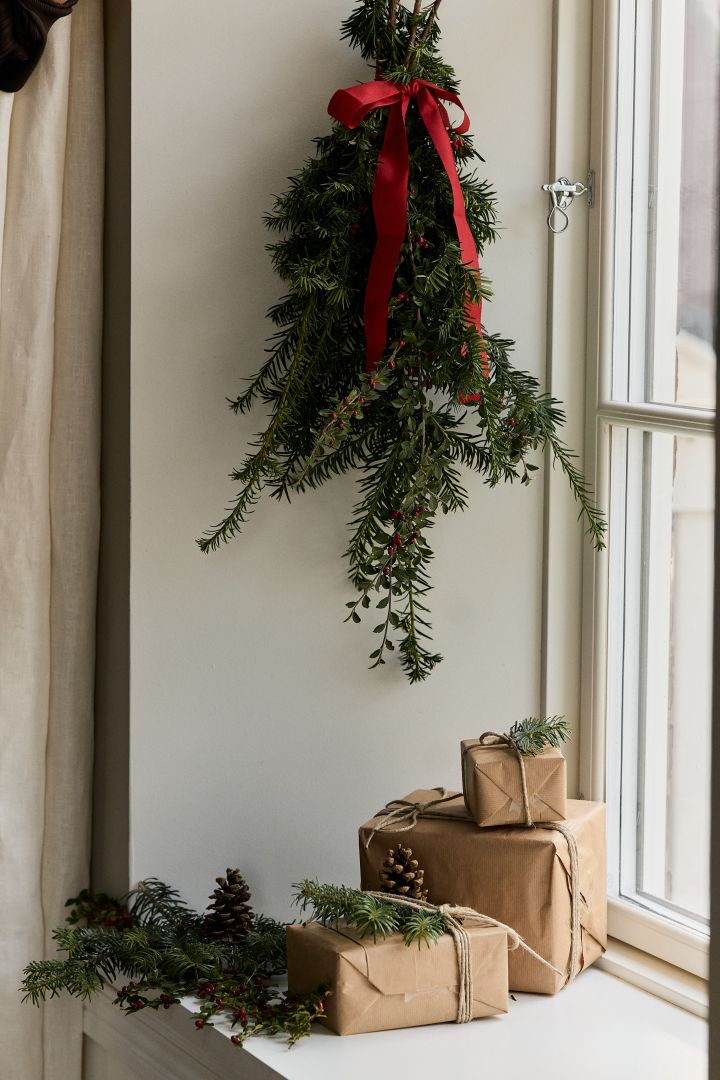 Pynta hemmet med granris dekoration för att skapa julstämning i hemmet. Här ser du en bunt med granris med en rosett knuten runt omkring.