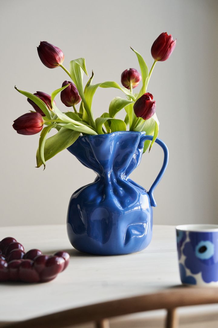 Inred enligt inredningstrender hösten 2023 och låt din inredning poppa med accenter i kornblått - här vasen Crumble från By On med röda tulpaner. 
