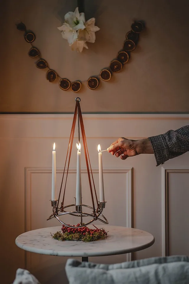 Season ljusstake med levande ljus tänds av Hannes Mauritzson i hans julinredda hem. 