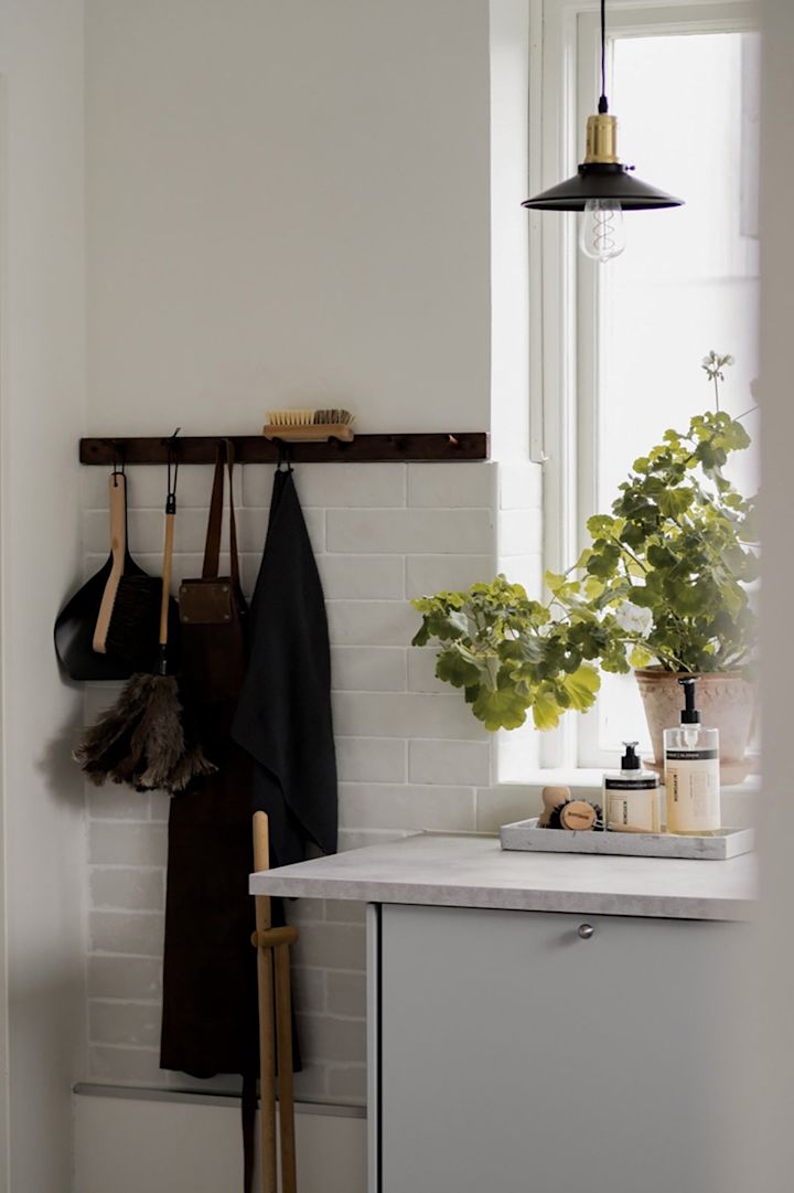 Mindre pendellampor ger punktbelysning i köket. Här kan du se Disc Mini pendellampa i svart från Globen Lighting hängande i ett kök framför ett fönster.