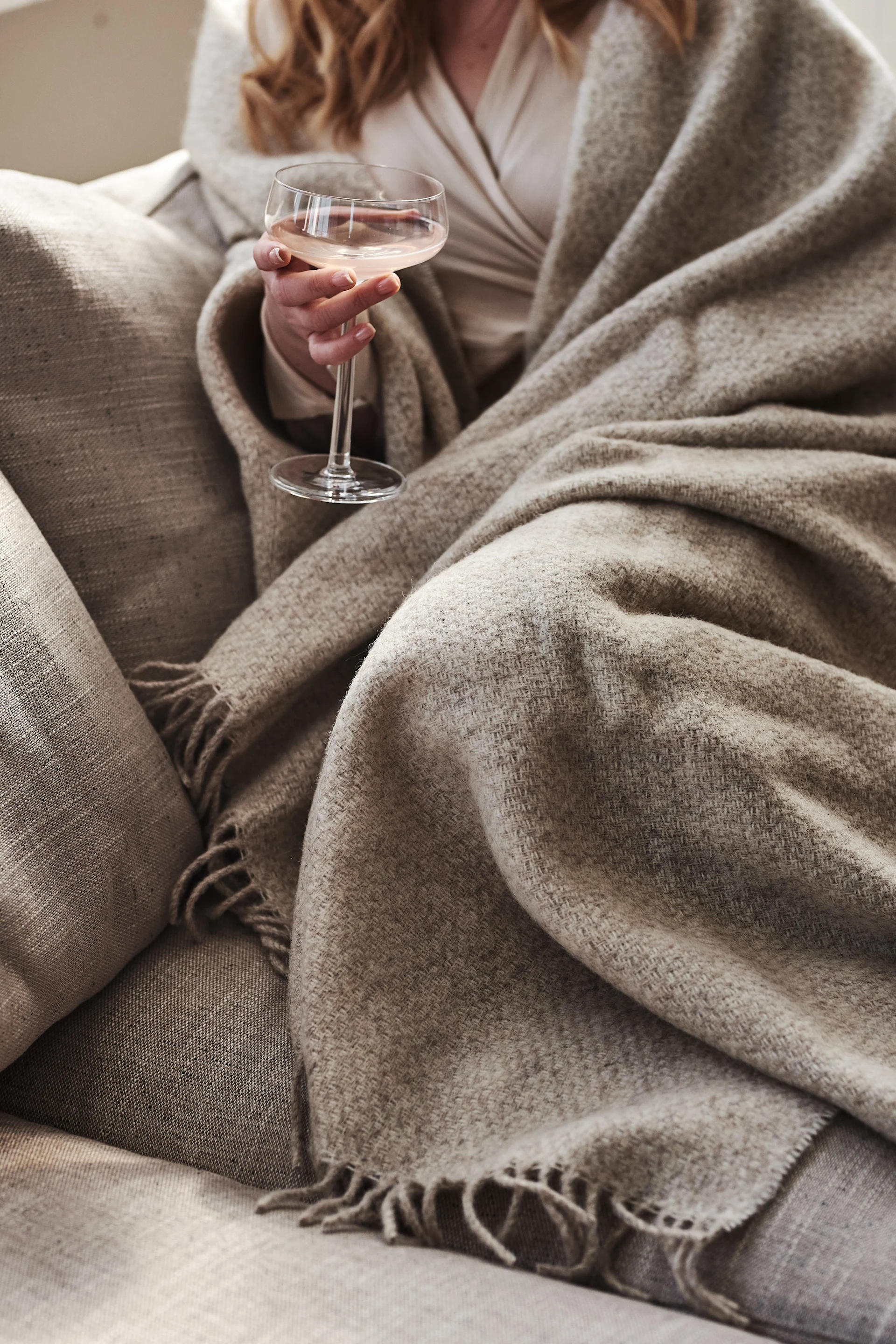 Kvinna insvept i beige ullpläd från Scandi Living. 