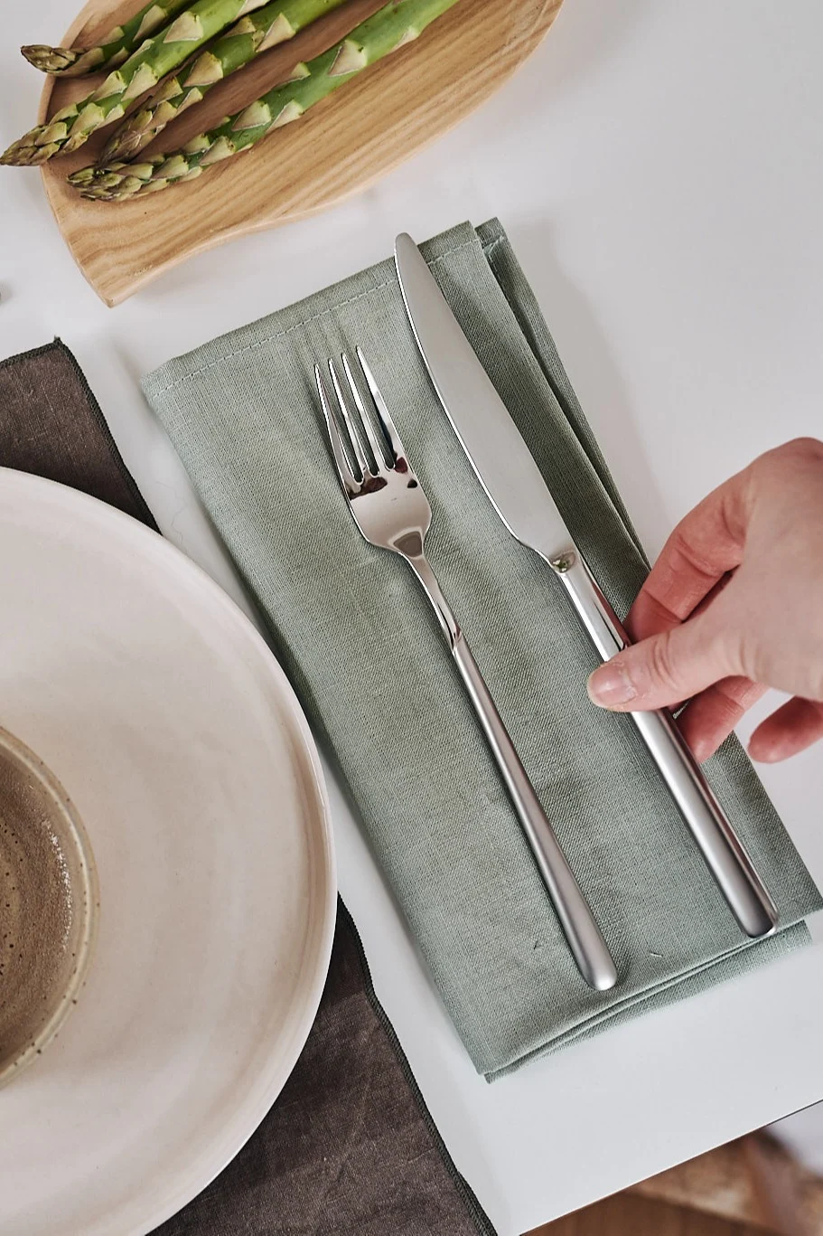 Dubbelvikt linneservett i grönt med bestick vilandes på från Scandi Living.
