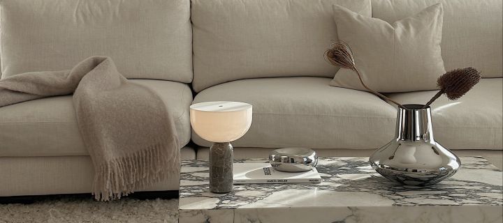 Influencern Helena Jonsson @helenas.hem har inrett med minimalistisk inredning i vardagsrummet med portabel belysning, ett soffbord i marmor och en silvrig vas.