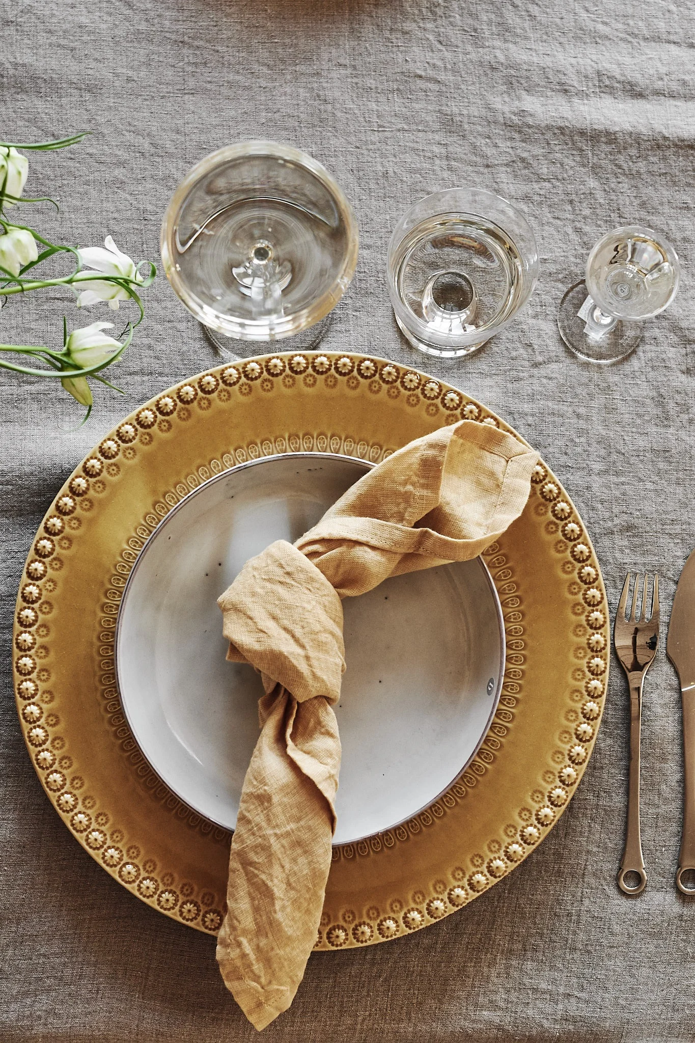 En festdukning i gula färger med gul linneservett ledigt knuten på tallriken.