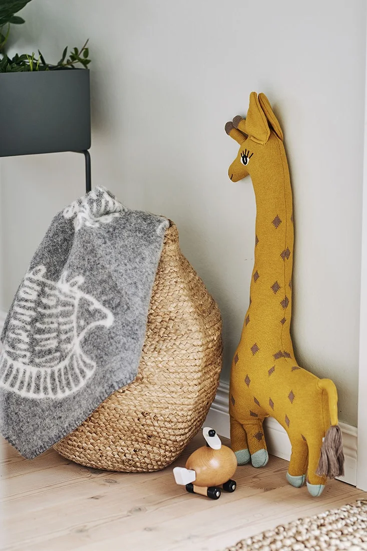 En barnpläd ligger ledigt nedstoppad i jutekorgen medan barnleksaker pryder ett hörn av matplatsen.