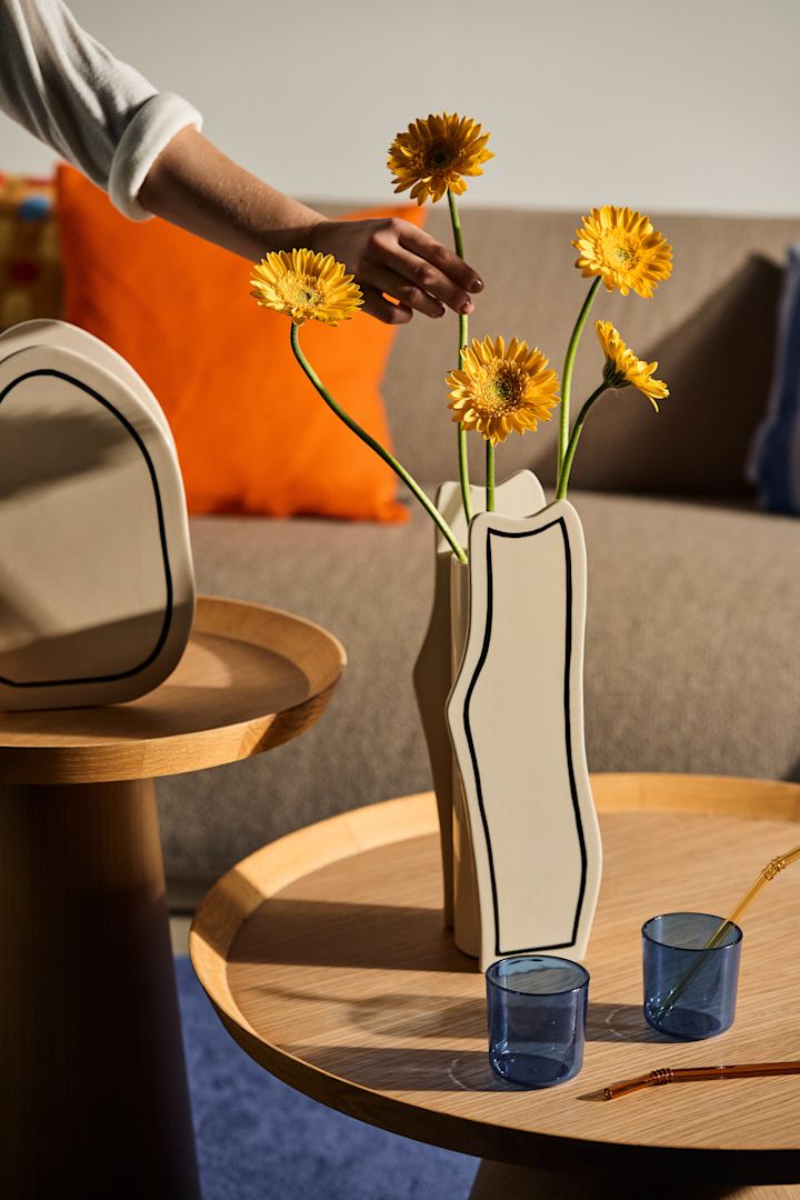 Bland inredningstrender 2024 ser vi mycket lekfulla former med retrovibbar. Här i svartvit vas från ferm Living med gula blommor i. 