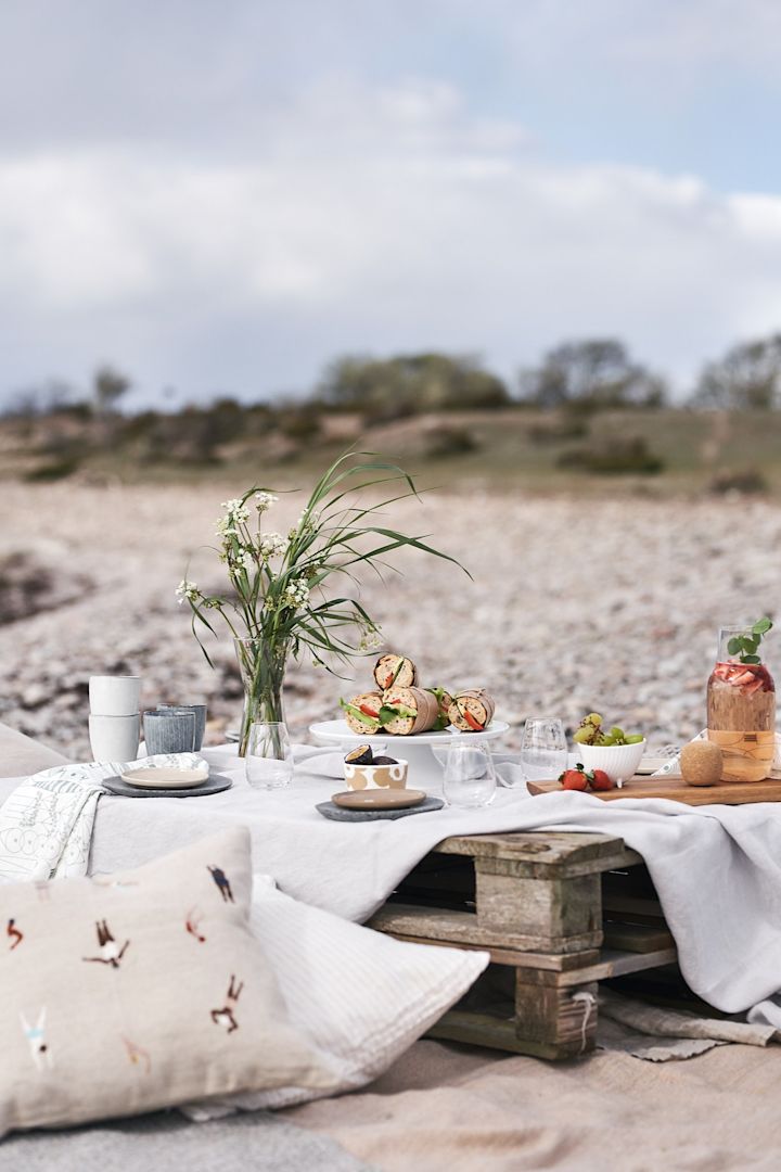 En lyxig picknick på stranden på lastpallar, med kuddar och enkel picknickmat. 