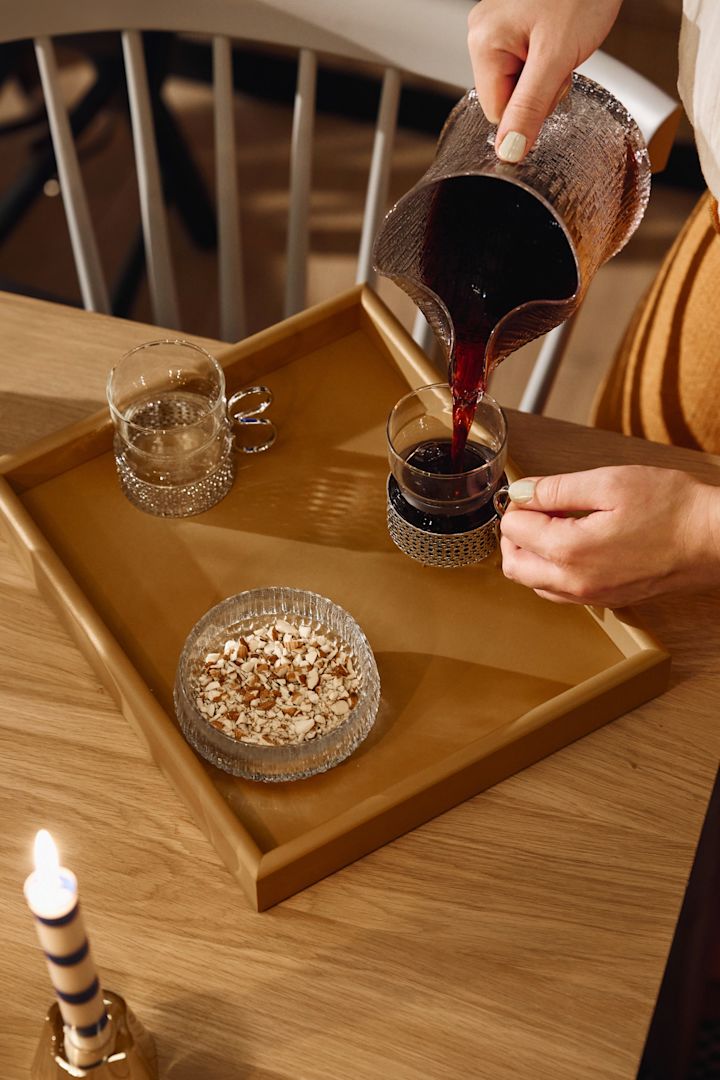 Glöggen hälls upp från en glaskanna i en glöggmugg av glas. 