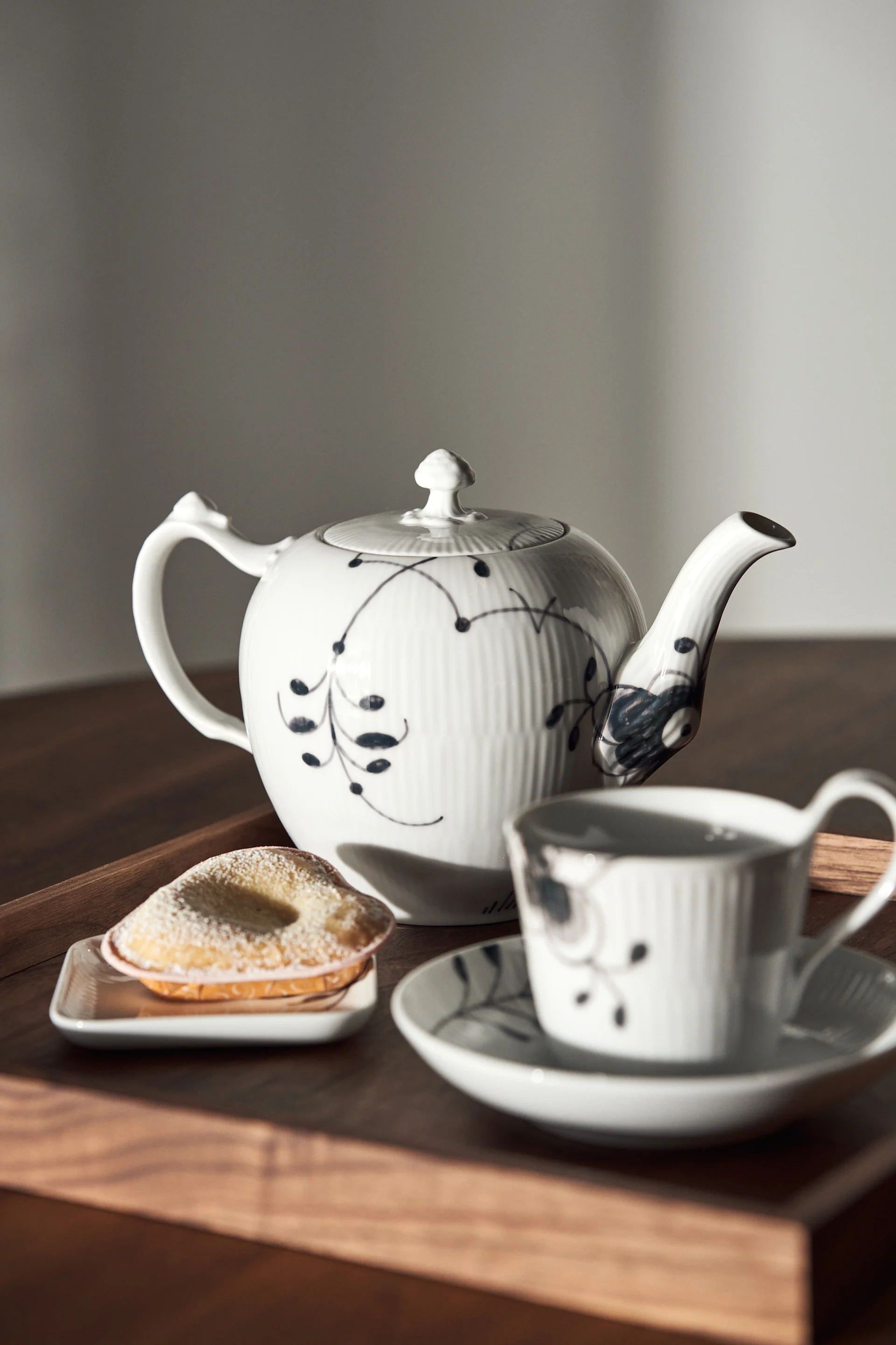 En bricka med Black fluted mega tekanna, tallrik och kopp med fat från Royal Copenhagen i svart och vitt - perfekt till fikastunden.