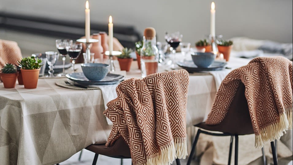 En ullpläd från Nordic Nest, vackert draperad över skinnstolen från House Doctor, visar på omtanke i denna trendiga dukning.