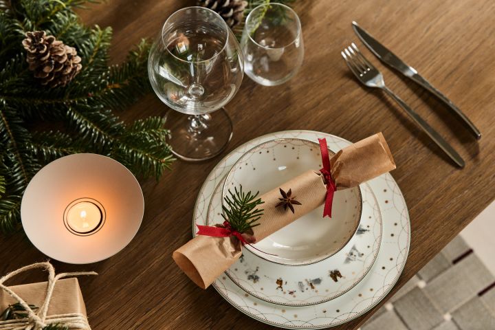 Enkel, elegant juldukning i vitt med serien Julemorgen från Wik & Walsøe med en smällkaramell som dekoration.