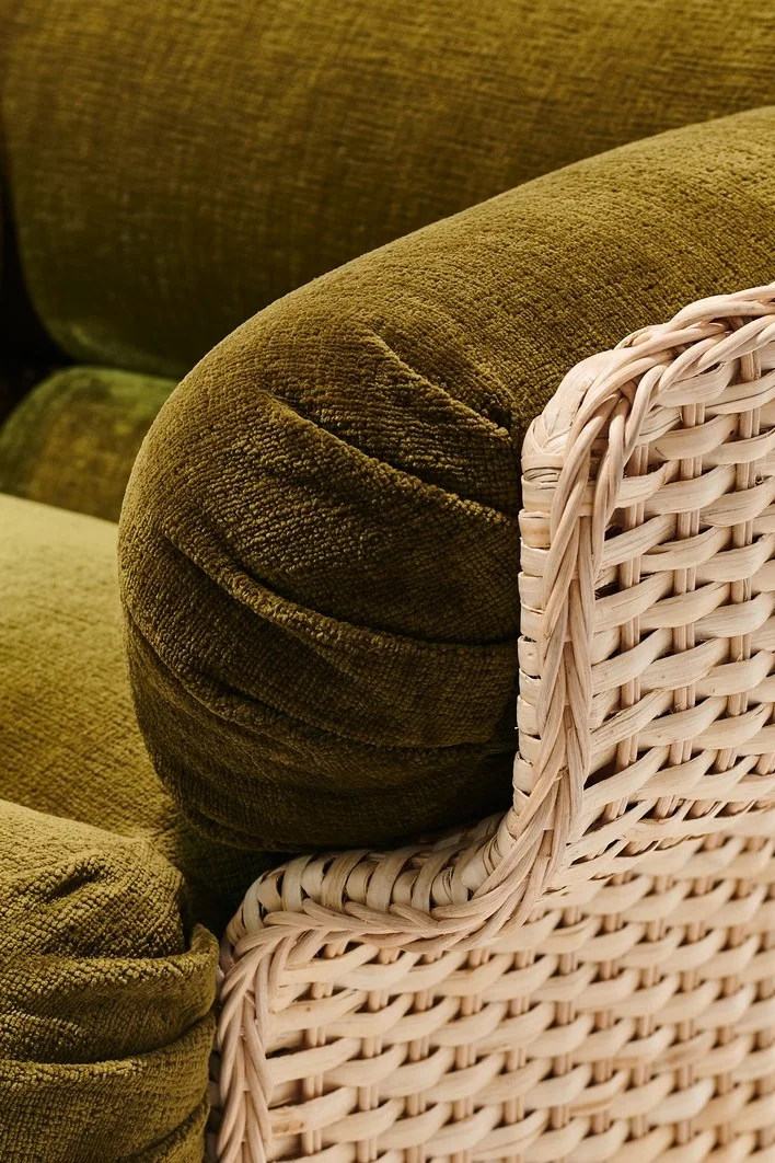Grova möbler är en av höstens inredningstrender 2025. Korgstolen från Gubi består av en rottingstomme och tjocka gröna kuddar.