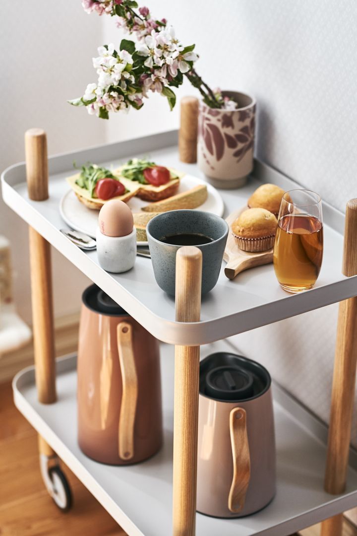 En riktigt lyxfrukost med kaffe, ägg och mackor står serverad på ett sidobord för en härlig frukost på sängen. 