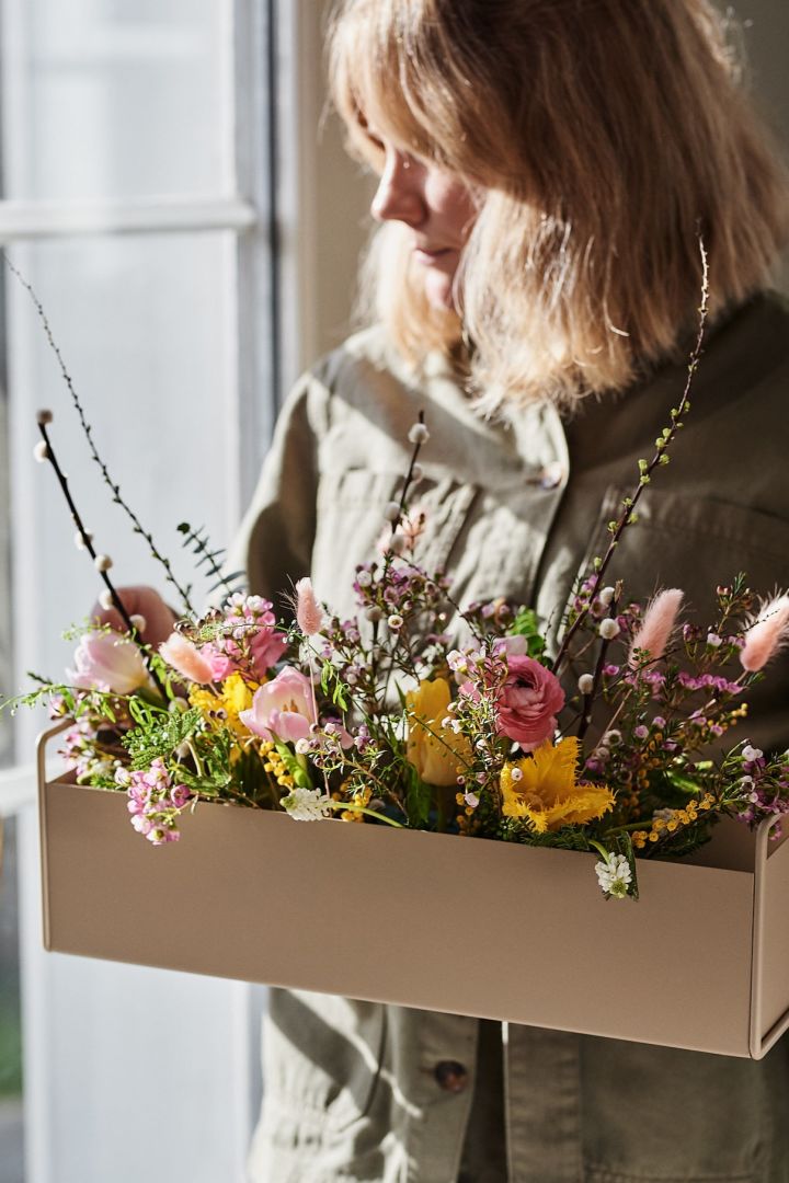 Liten, bärbar Plant Box från Ferm Living fylld med vårens snittblommor som vilar i en blötlagd oasis. 
