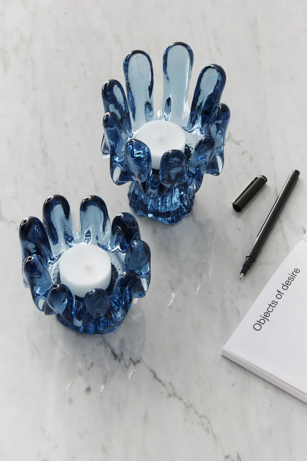 Höstens inredningstrender 2025: Två blå ljusstakar från kollektionen Solros av Kosta Boda står på ett ljust bord.