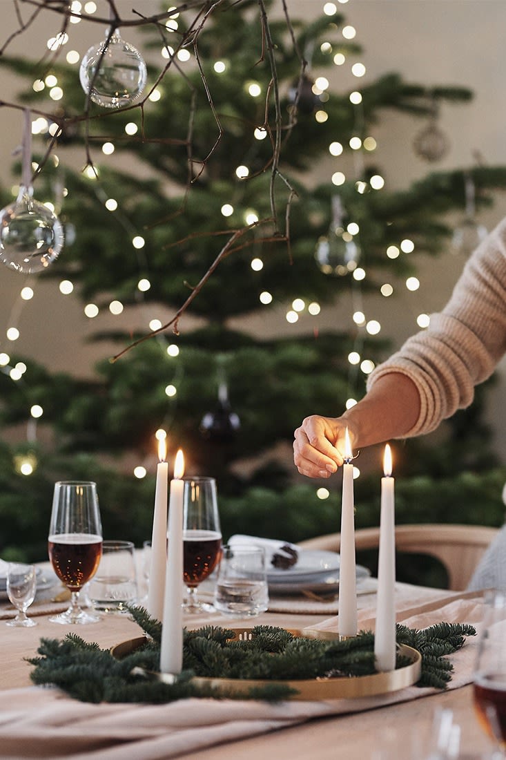 Det fjärde ljuset tänds på adventsljusstaken på en vit juldukning inspirerad av naturen. 