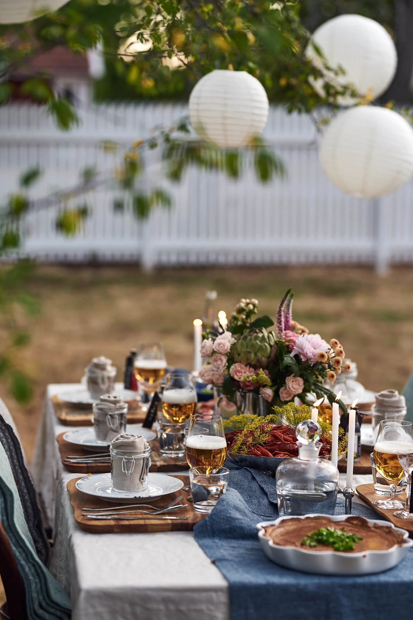 Bordet står uppdukat och redo för gästerna. Kräftorna ligger på plats och stämningsfulla ljus i både träd och på bord skapar en gemytlig stämning.