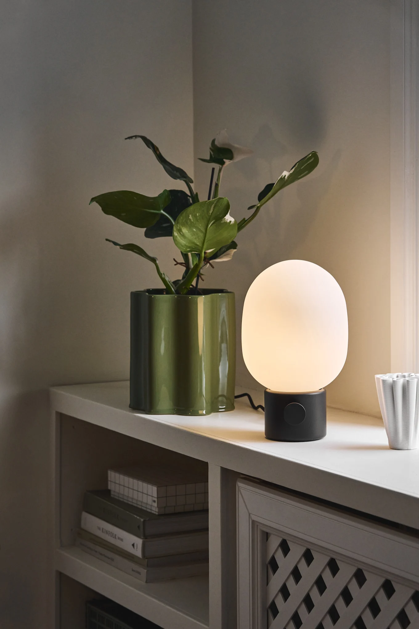 Skandinavisk belysning: JWDA table lamp från Audo Copenhagen står på en fönsterbräda bredvid en blomkruka.