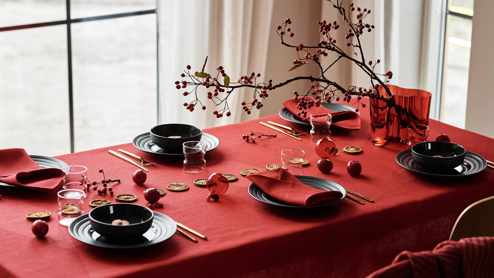 Skapa en stämningsfull juldukning 2025 med en röd linneduk som grund, kompletterad med svart, modernt porslin och röda linneservetter för en tidlös men trendig look.