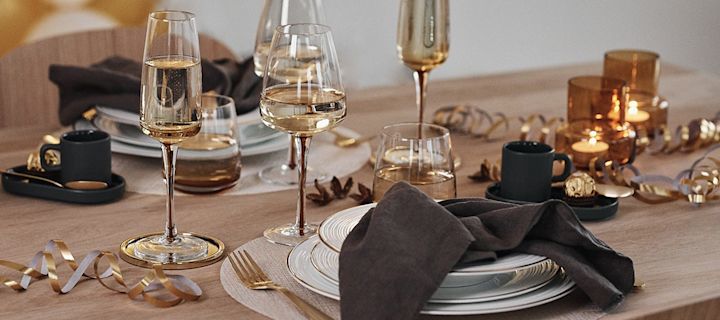 Nyårsdukning i guld med bärnstensfärgade glas och vitt porslin med guldkant.