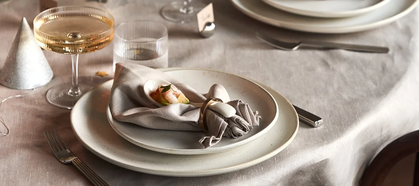 Ett bord dukat till nyår med en servettvikning som föreställer ett blad som en stil på servettvikning till årets nyårsfest.