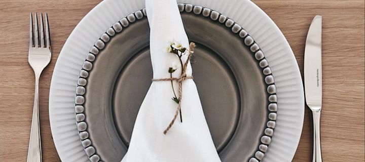 En sommardukning med blandat porslin i neutrala jordiga toner där vit mattallrik från Eva Solo kombinerats med brun assiett från PotteryJo.