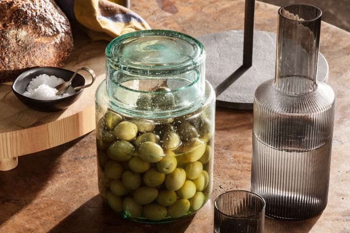 En av höstens inredningstrender 2021 är att finna gemenskap i köket genom att investera i fint porslin eller som här - Ferm Livings Ripple glas och karaff eller förvaringsburk från Ferm Living att förvara oliver i.