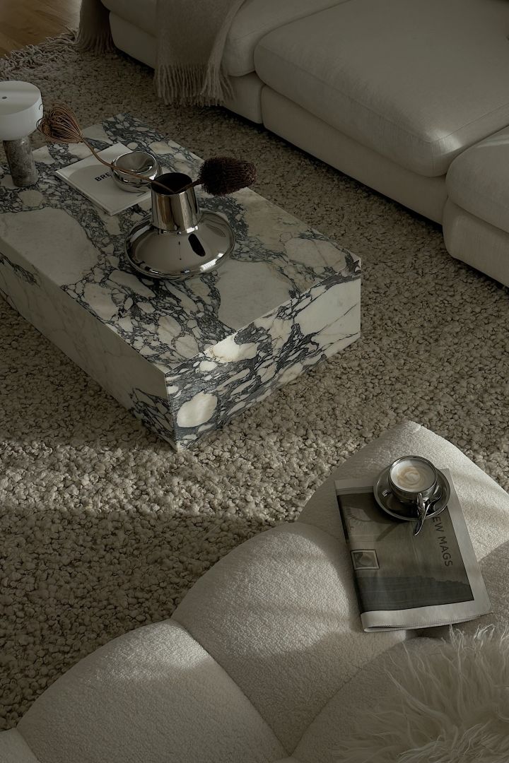 Influencern Helena Jonsson @helenas.hem har inrett med minimalistisk inredning i vardagsrummet med ett soffbord i marmor, portabel belysning och silvrig vas.