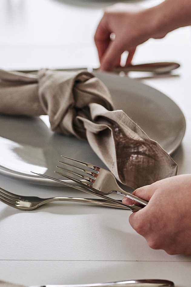 Enkel dukning med Hardanger bestick, linneservett och grå Norm assiett från Menu. 