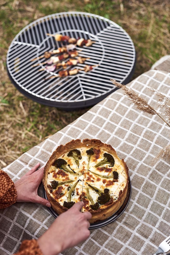 Picknickmat med broccoli- och fetaostpaj som skärs. 