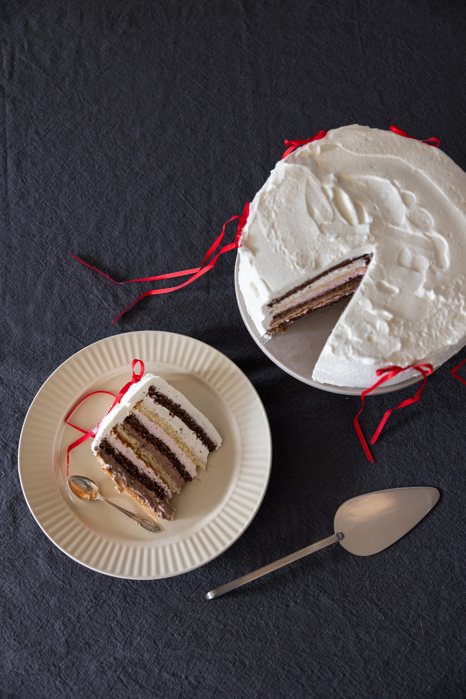 En gräddtårta på en tallrik, bredvid ett tårtbit på en annan tallrik från Coffee & More-kollektionen från Sagaform i beige.