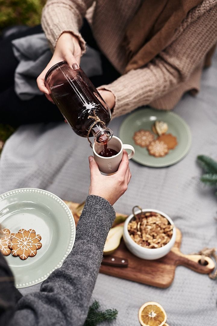 Glöggmys med pepparkakor och nötter avnjuts i på marken i skogen. 