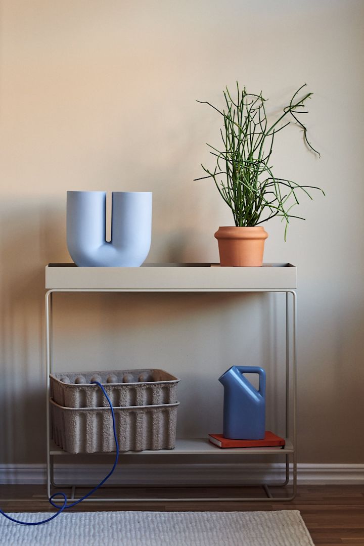 Inred ditt vardagsrum med beige inredning i kombination med färg för ett livfullt intryck i ditt hem. Här ser du mångsidiga och praktiska Plant Box konsolbord från Ferm Living i beigt tillsammans med blå Kink vas och Tub kanna från Muuto.