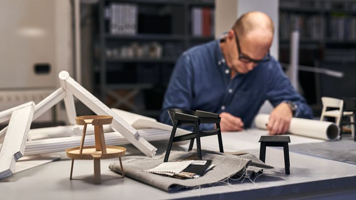 Thomas Bentzen skissar i sin studio i Köpenhamn med prototyper av Cover-stolen och Around-bordet runt sig. 